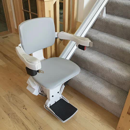 Bruno Elite straight stairlift with a gray padded seat on a carpeted indoor staircase